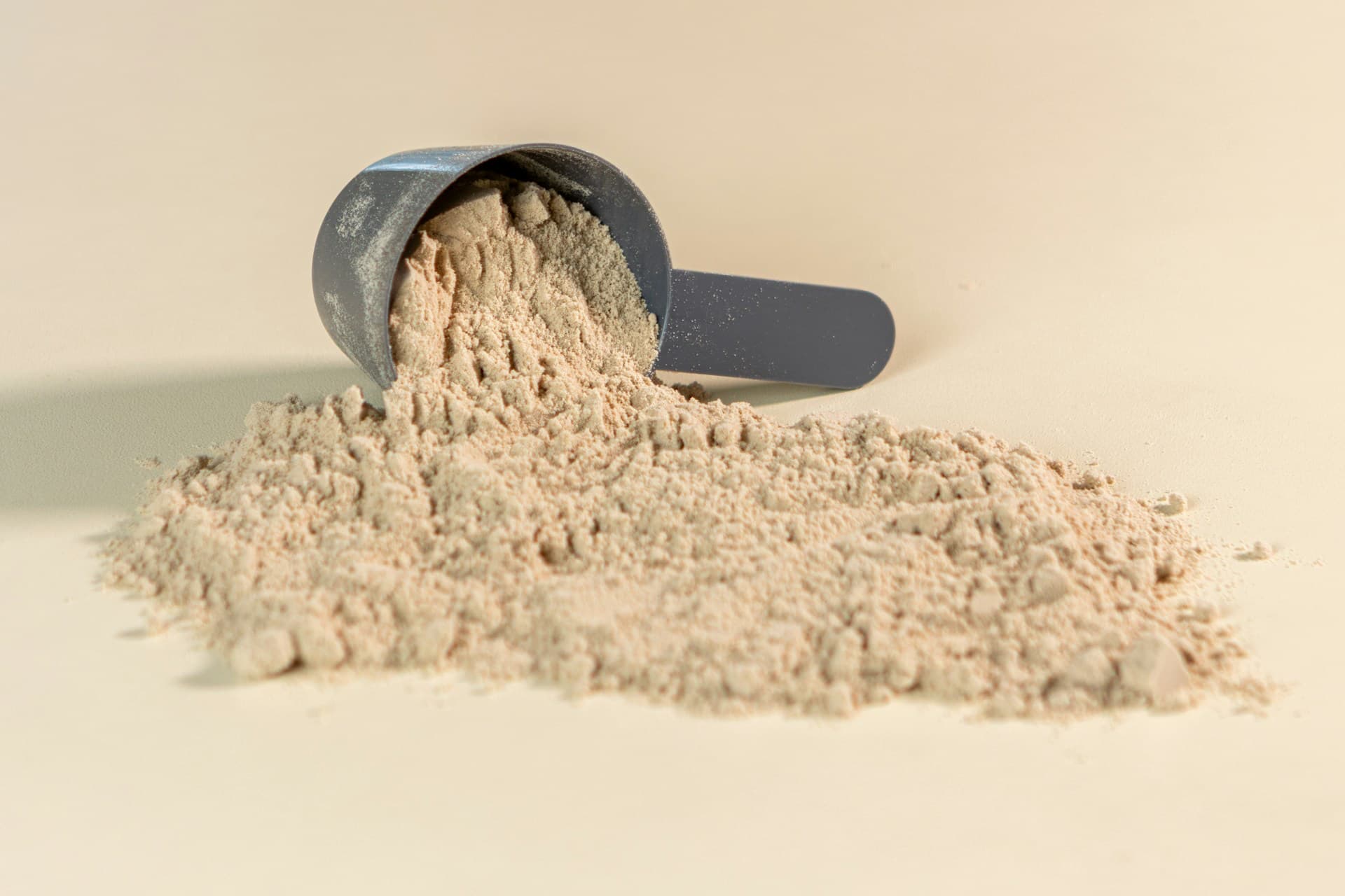 Scoop spilling protein powder on a light background